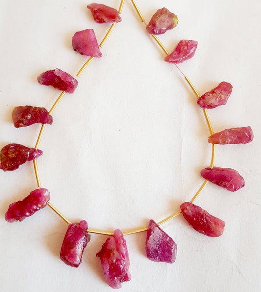Ruby beads in rough cut side-drilled layout featuring vivid red hues and organic surface texture.