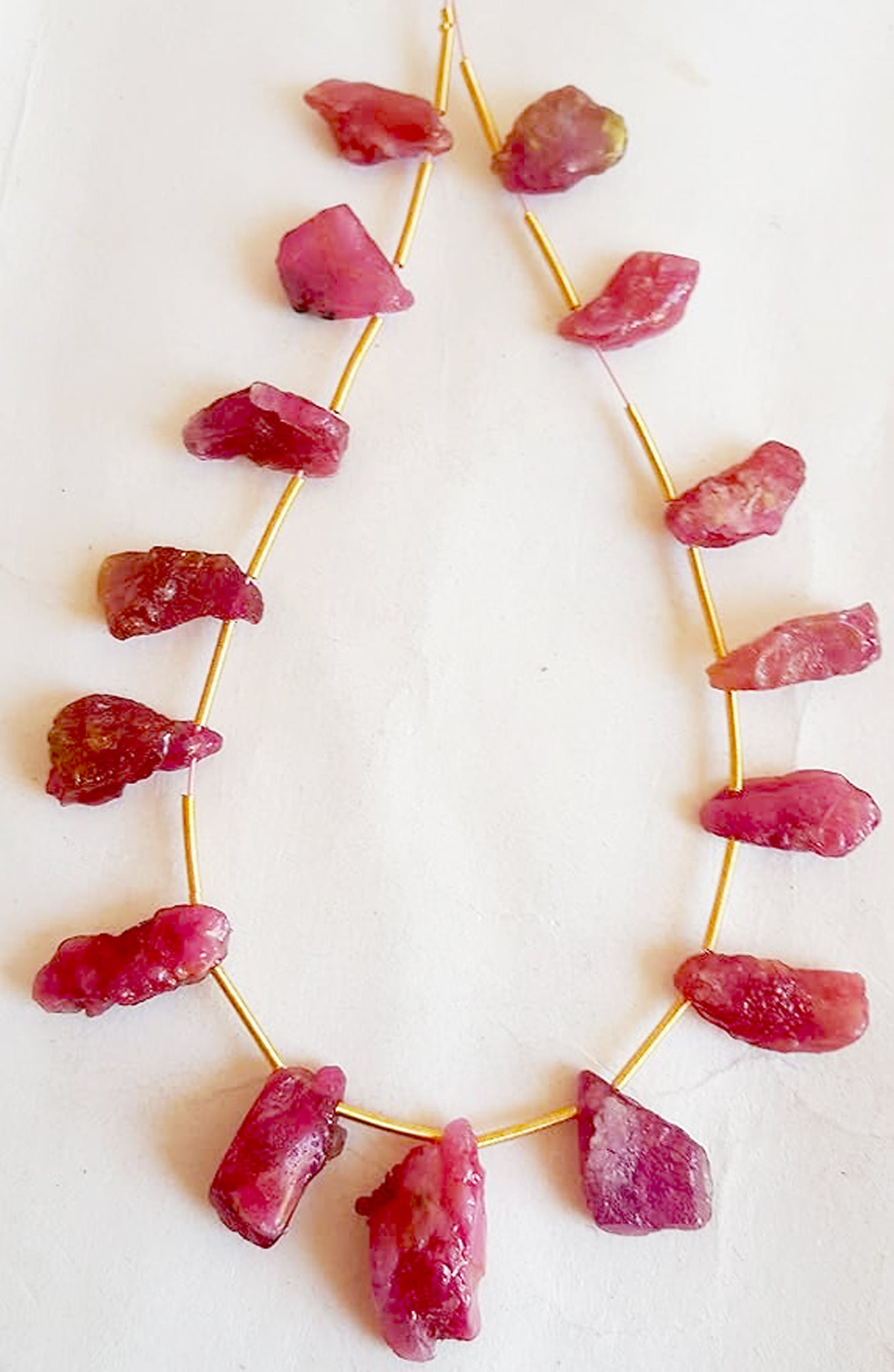 Ruby side-drilled beads with rugged finish displayed in a linear strand arrangement.