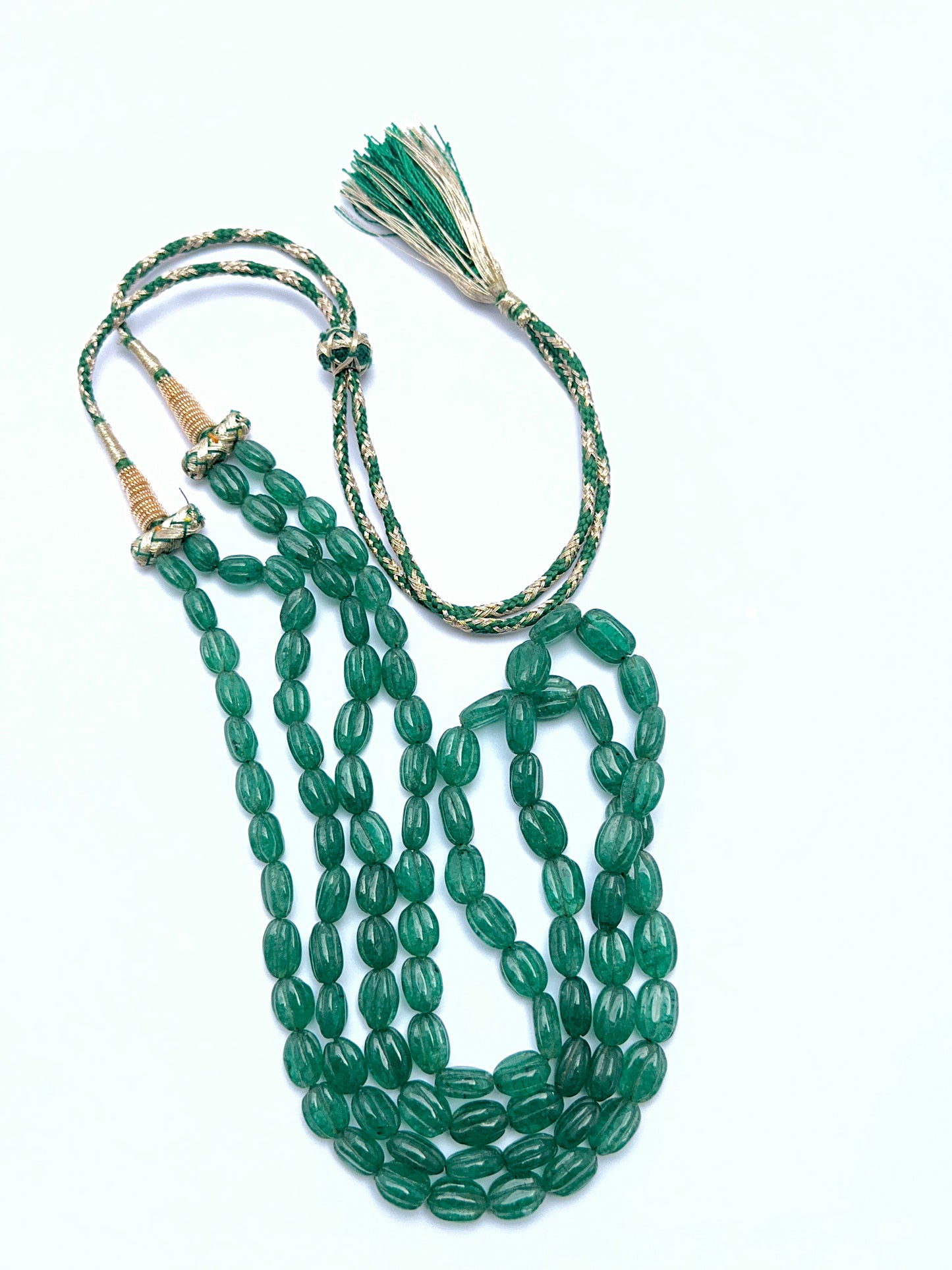 Emerald necklace with carved oval beads arranged in a polished layout.