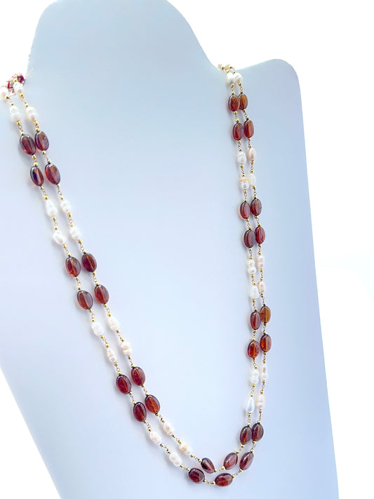 Close‑up of hessonite and pearl beads arranged on a polished two‑strand necklace.