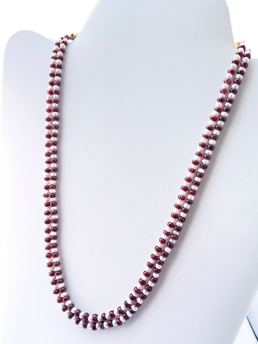 Close‑up of ruby rondelle beads and pearls arranged on a polished necklace.