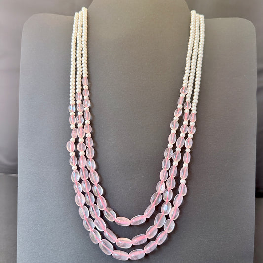 Close-up of polished rose quartz oval beads and round shell pearls with gentle lustre.
