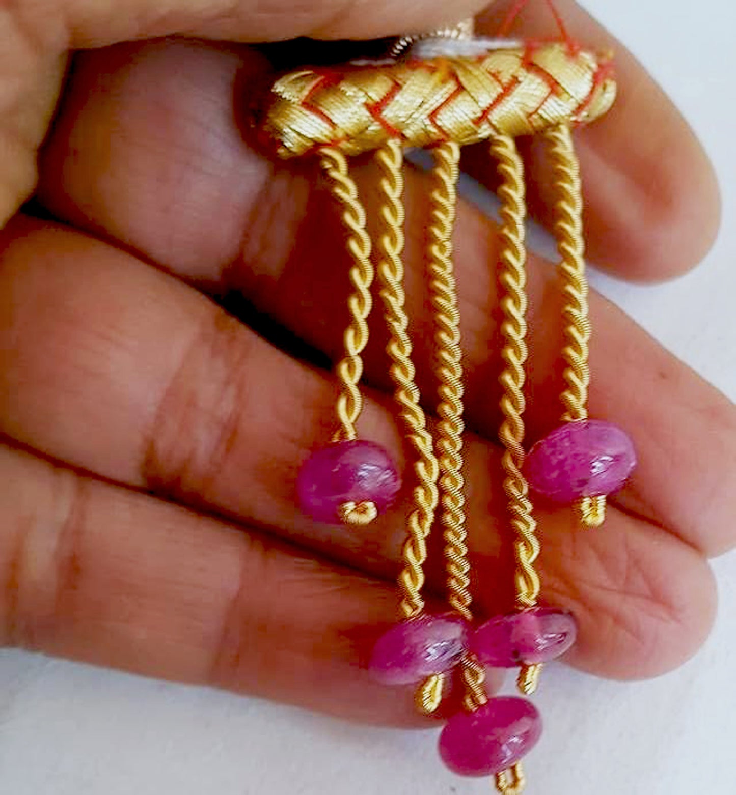 A person holds delicate strands of ruby beads, showcasing their smooth design.