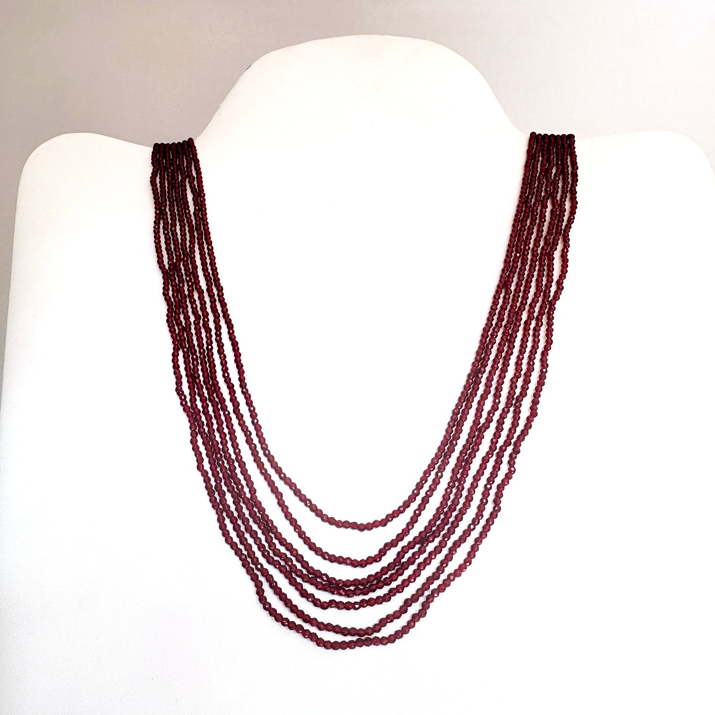 Seven-strand chalcedony necklace with ornate clasp, crafted from polished natural gemstone beads in deep red tones.