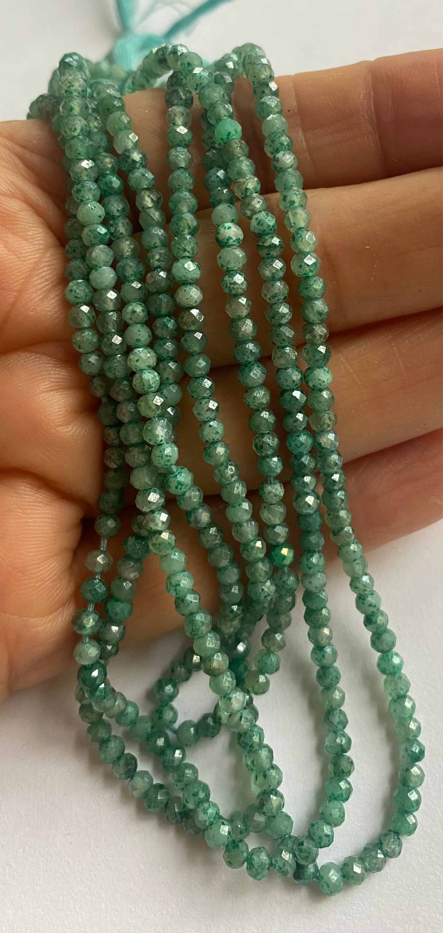 A strand of green amazonite beads, featuring 3mm to 3.5mm faceted rondelle shapes, showcasing their vibrant colour and shine.