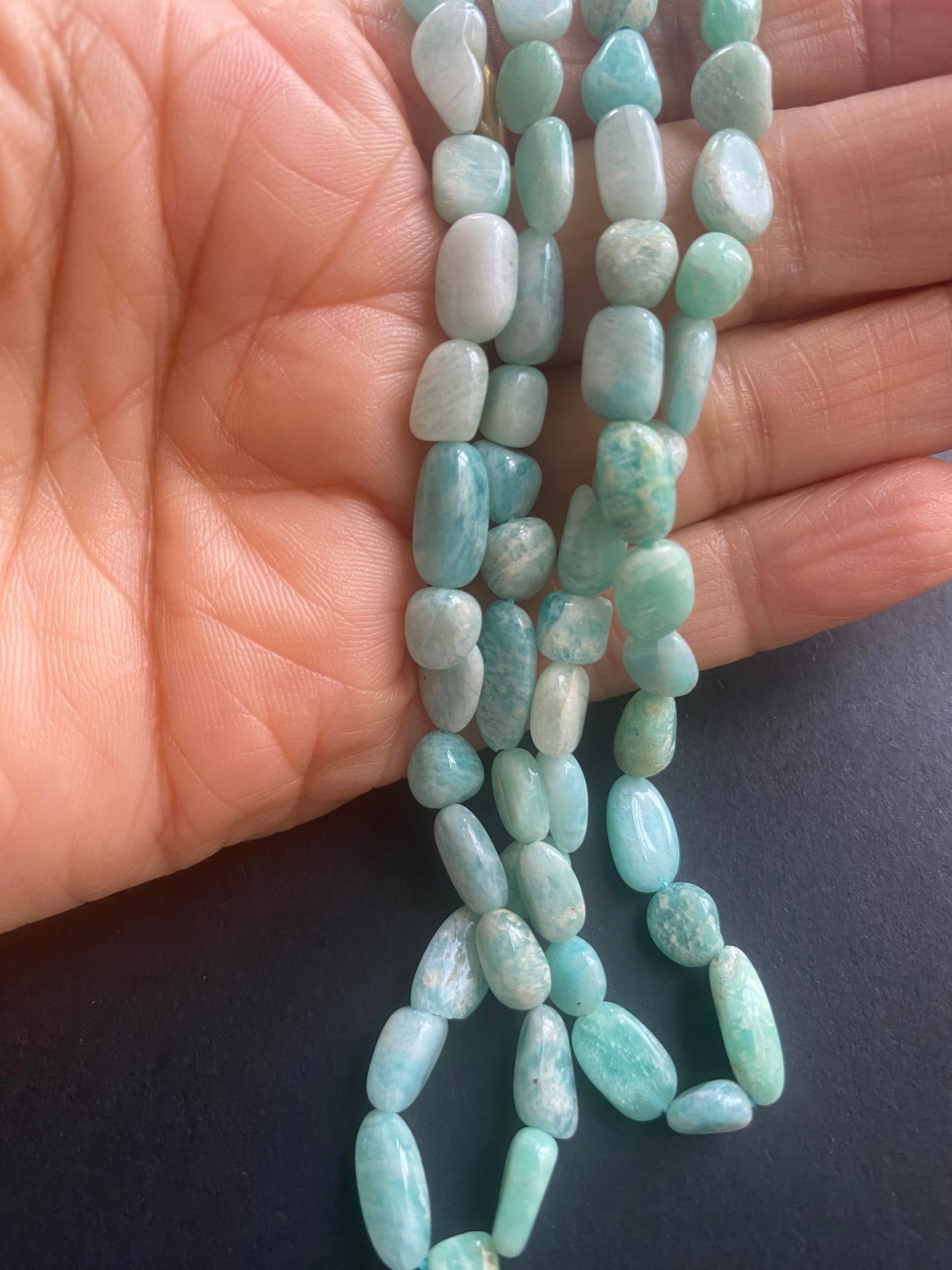 A strand of green amazonite beads, featuring 5.5-6mm smooth tumble shapes, showcasing their vibrant colour and shine.