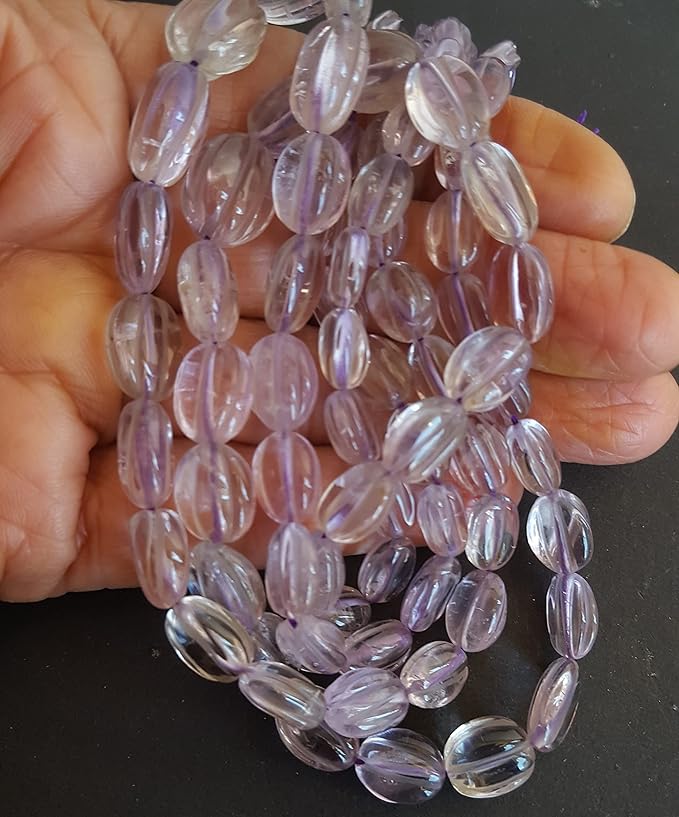 Close-up of a person holding a stunning purple amethyst gemstone strand, highlighting its intricate facets.