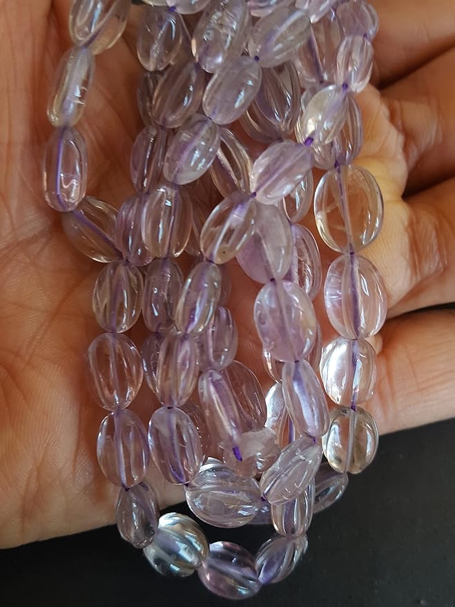 A person holding a craved smooth oval amethyst gemstone strand, showcasing its purple facets and elegant design.