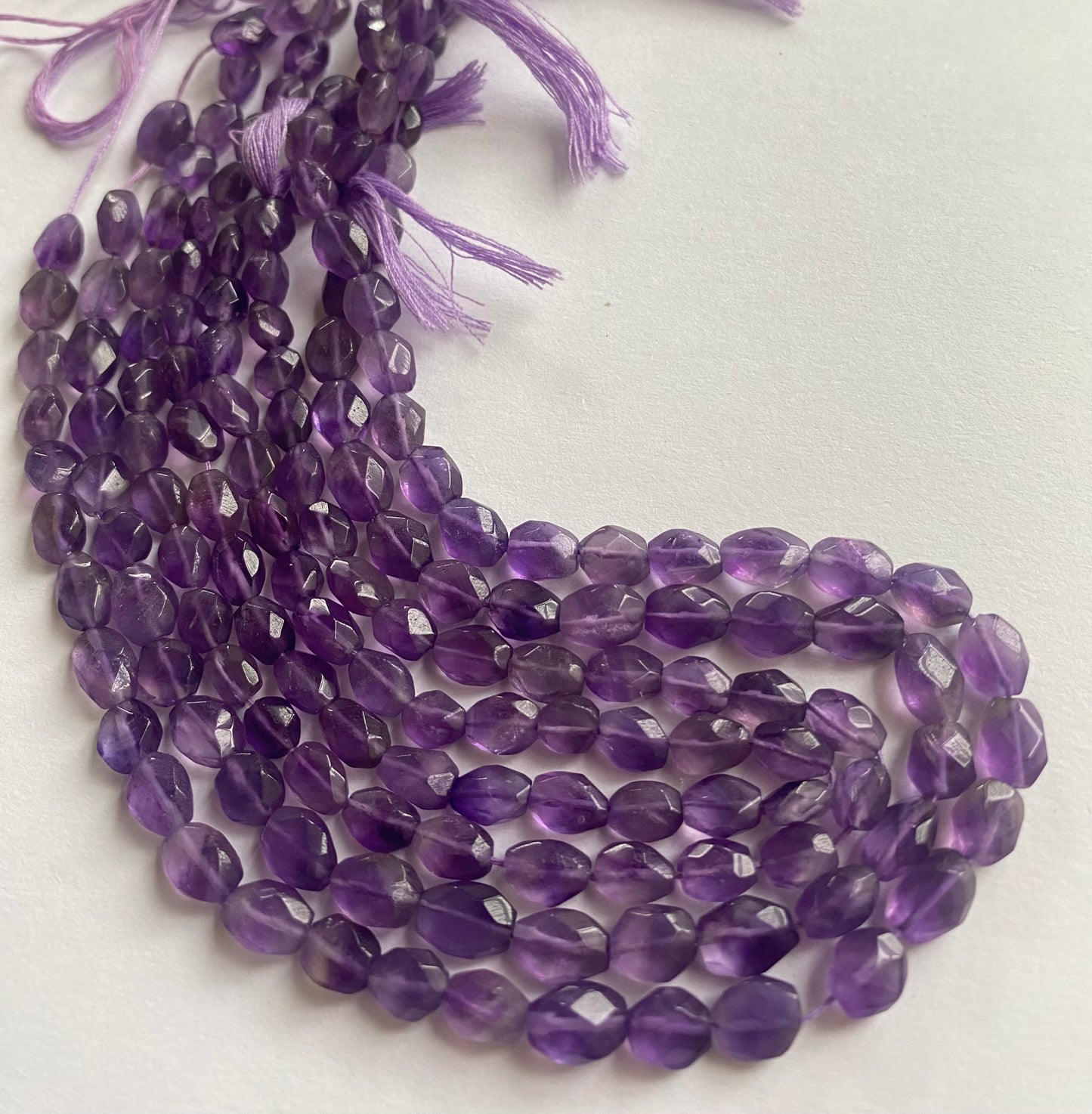Strand featuring faceted oval amethyst gemstones, ranging from 5.5mm to 6.5mm, in a stunning purple hue.