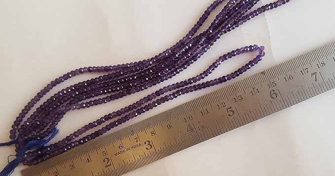 Close-up of a measuring ruler alongside green Amethyst beads, showcasing their faceted rondelle shape and size.