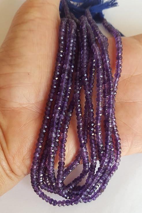 Close-up of a person holding a stunning purple amethyst gemstone strand, highlighting its intricate facets.