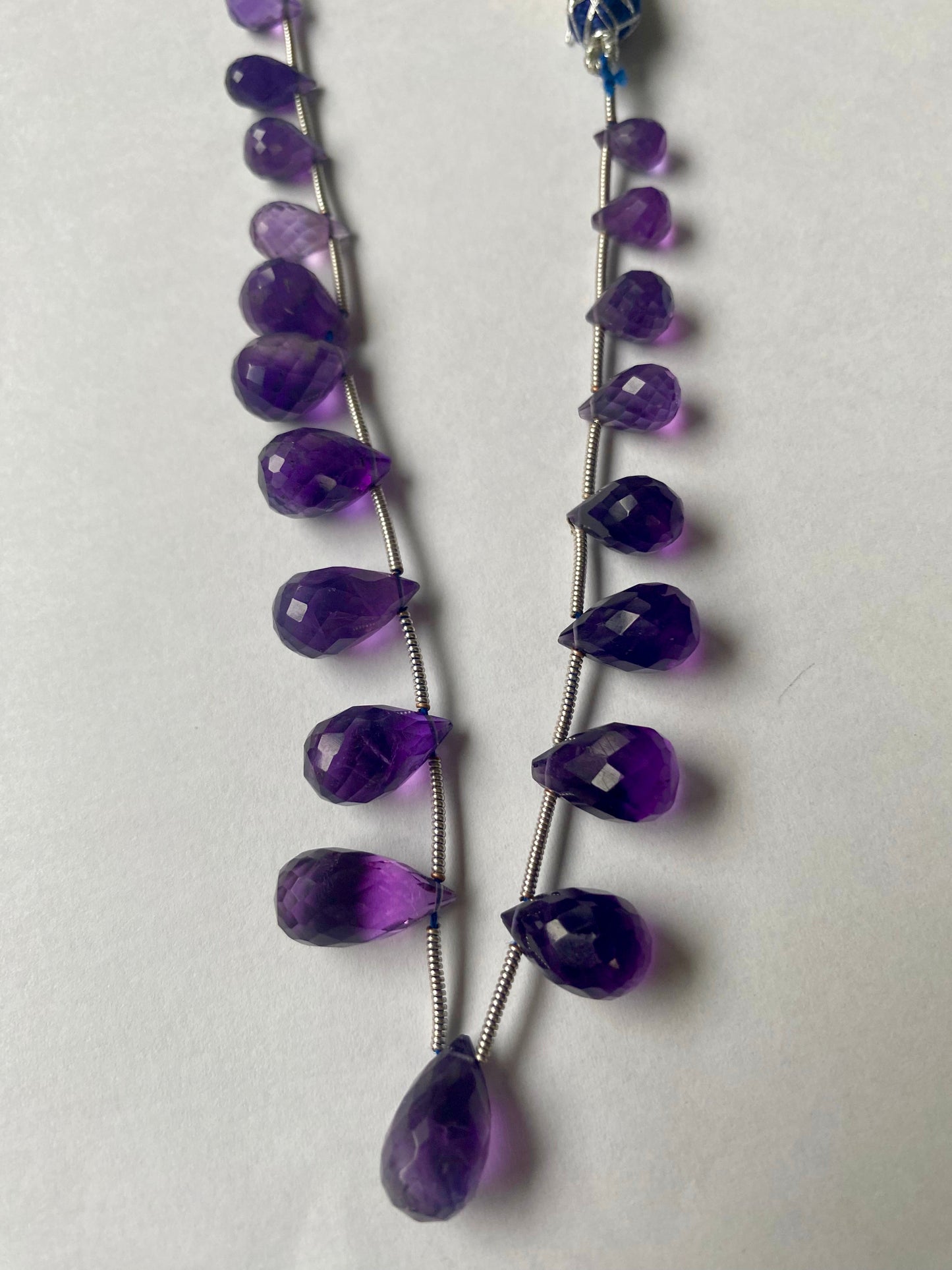 Beautiful purple amethyst stones, teardrop-shaped and faceted, measuring between 5mm and 8mm.
