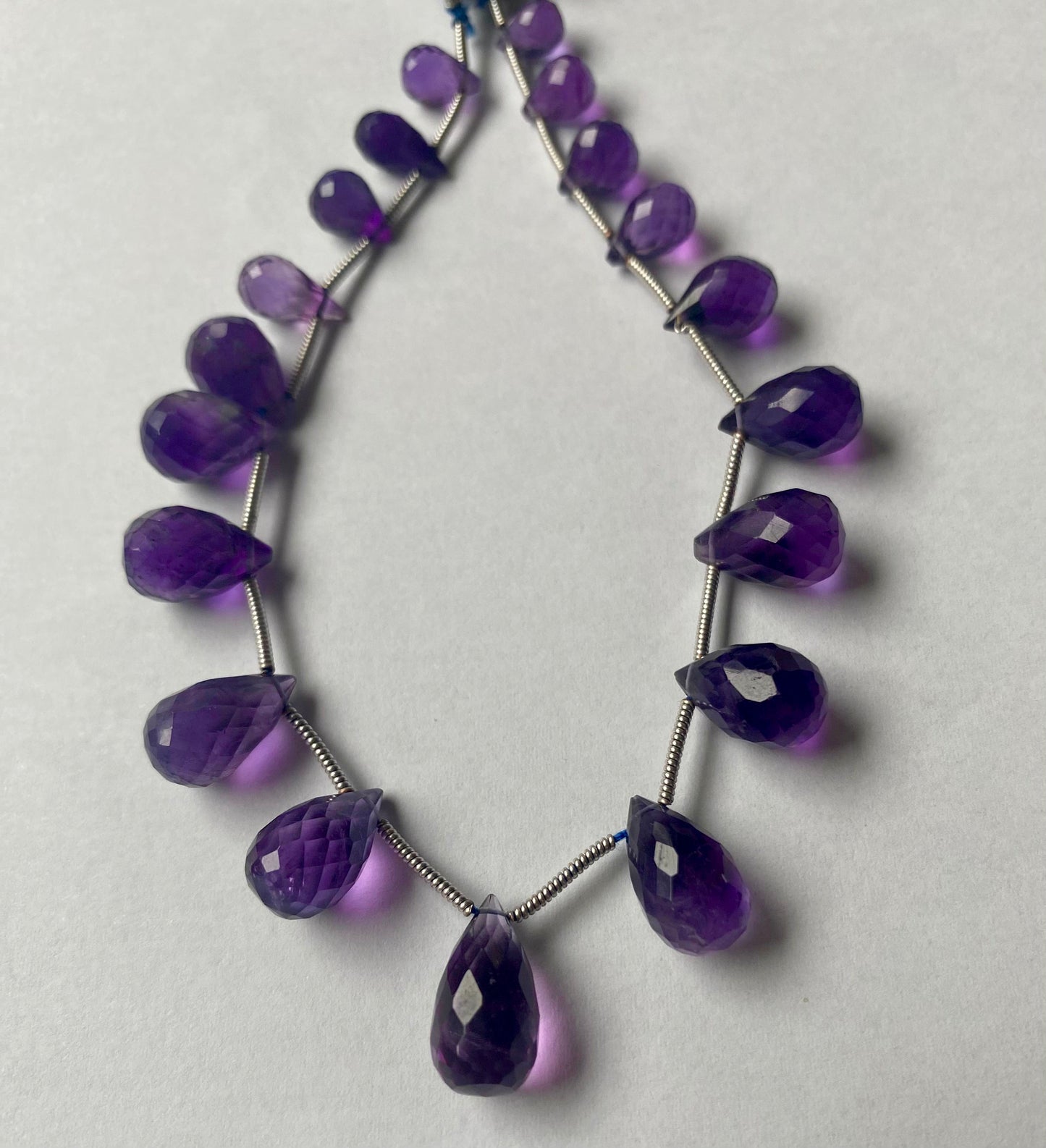 Strand featuring faceted tear drop amethyst gemstones, ranging from 5mm to 8mm, in a stunning purple hue.