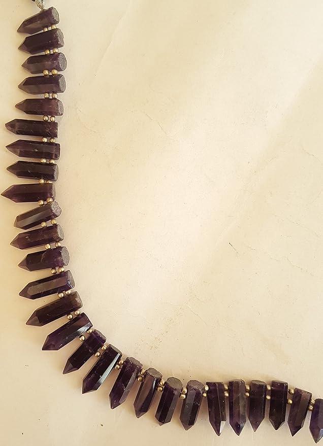 A close-up of a strand featuring purple beads displayed on a sleek white surface, highlighting its vibrant colour contrast.