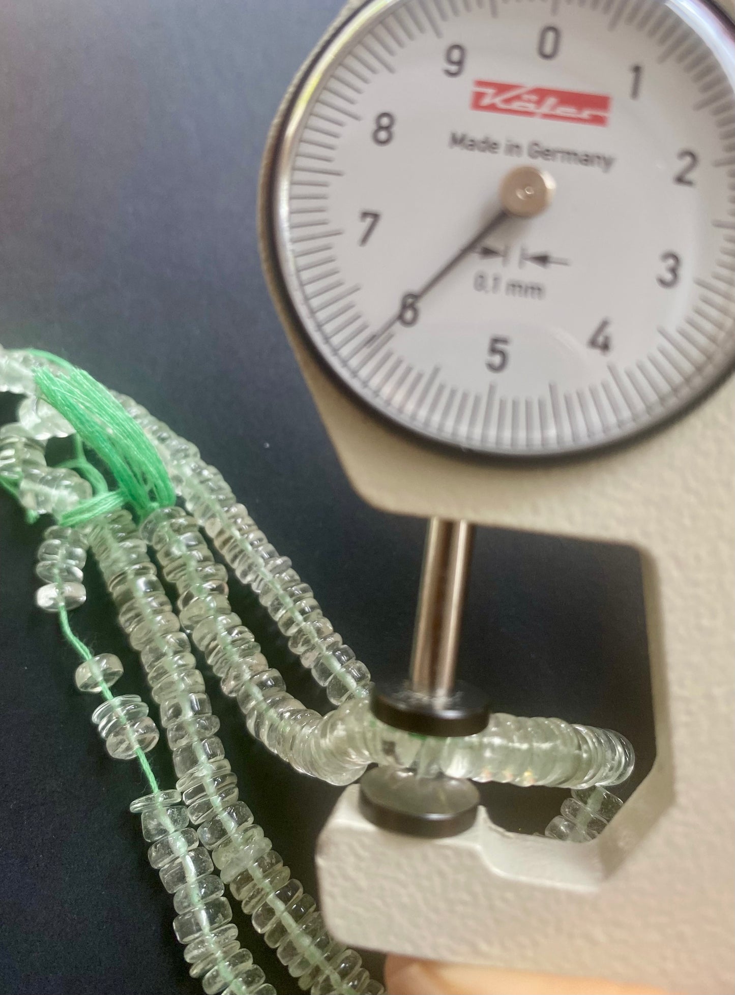 A dial gauge measures the Amethyst Smooth Wheel 5.5-6.0mm gemstone.