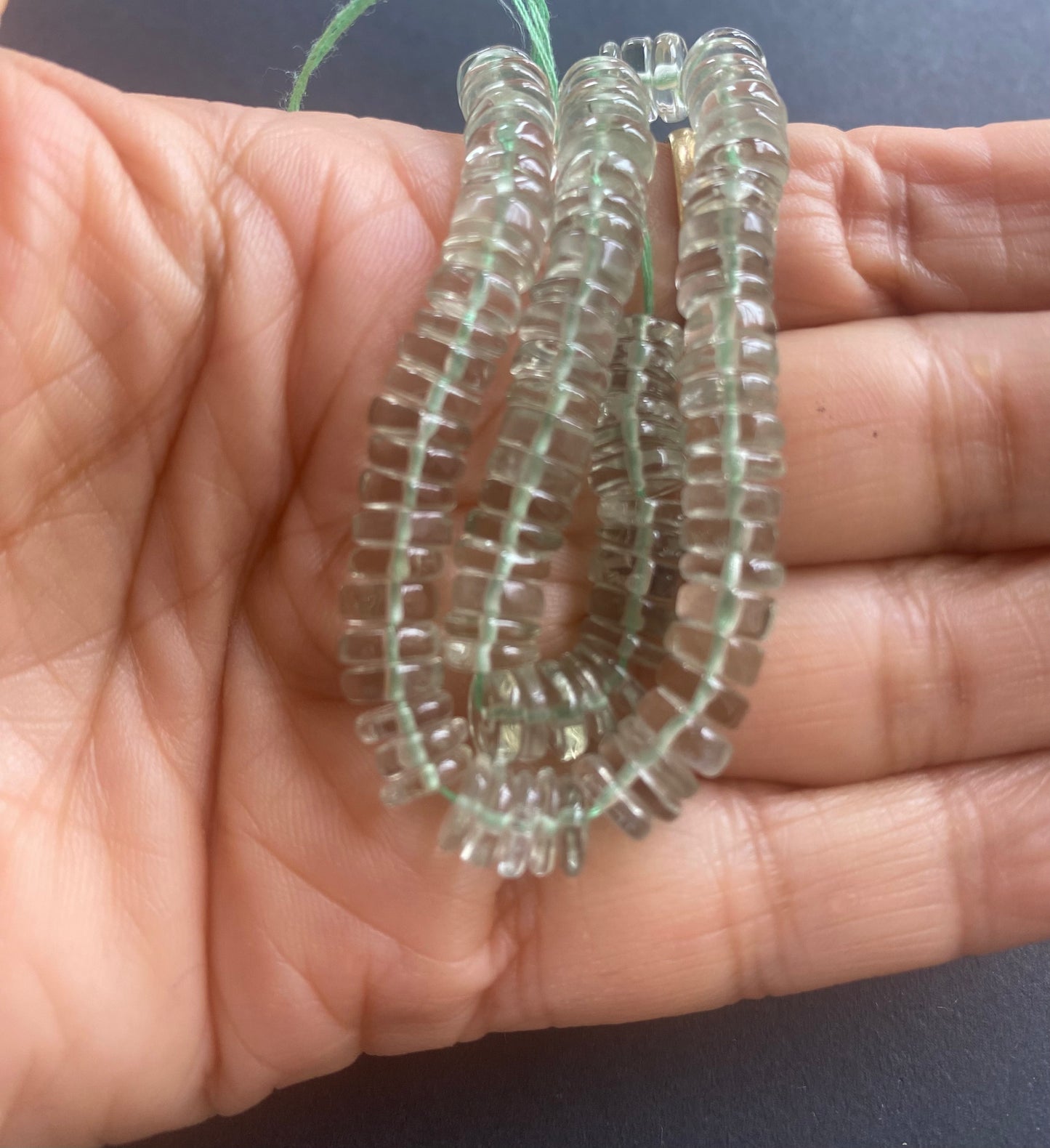 A person holding a smooth wheel amethyst gemstone strand, showcasing its elegant design.