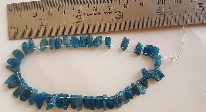 A person measures a blue Apatite Raw Rough Side Drilled, ranging from 4mm to 5mm, using a dial gauge measuring tool.