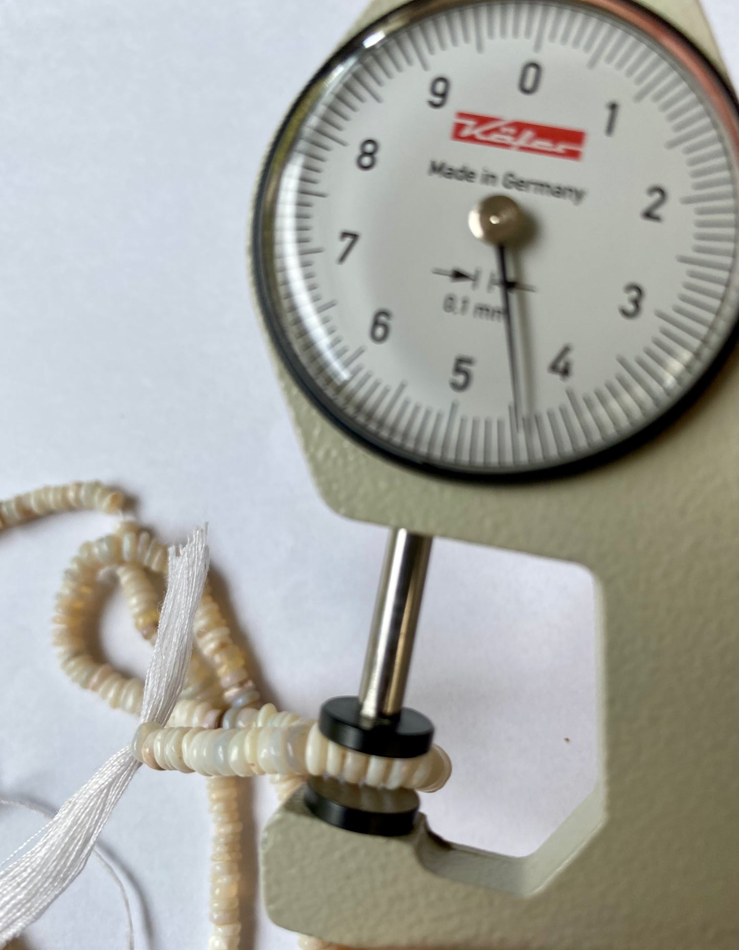 Detailed view of a measuring dial gauge and gemstone bead, emphasising the dimensions for crafting Australian Opal pieces.