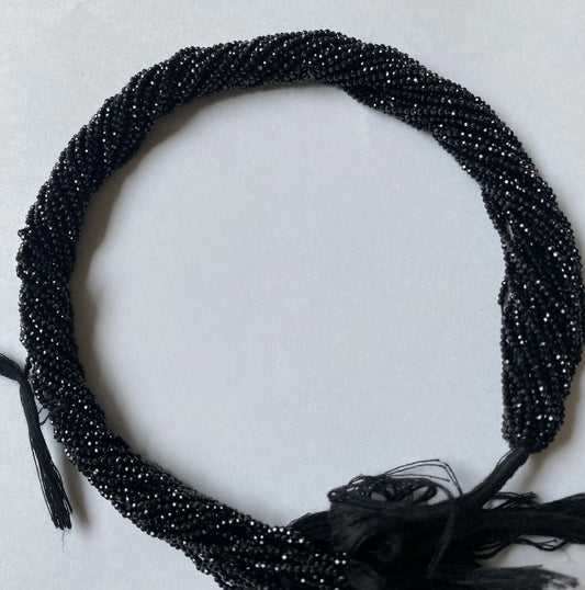 A close-up of a multiple strands featuring black spinel micro-faceted rondelle beads, measuring 2-2.5mm in size.
