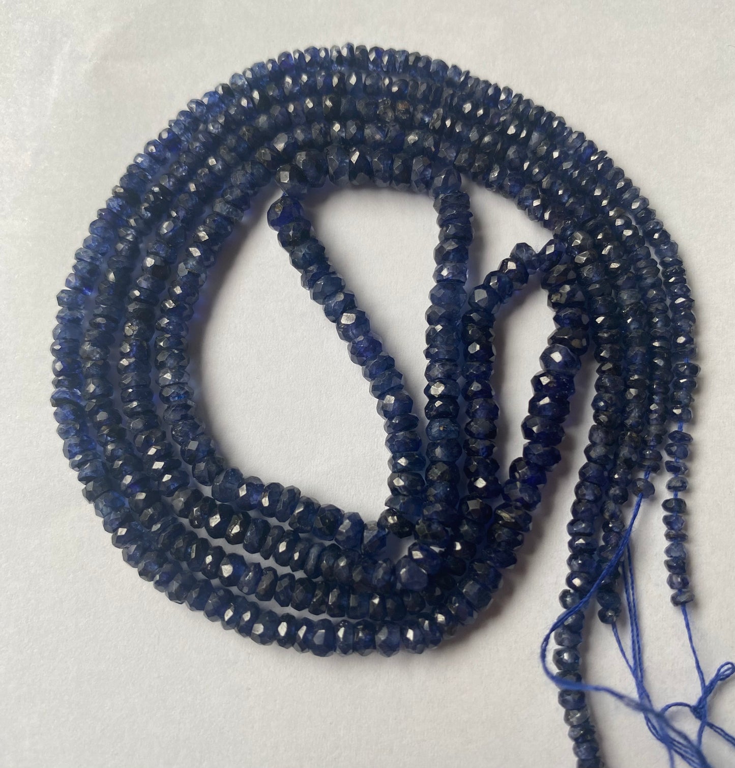 A strand of faceted blue sapphire rondelle gemstone beads, measuring 2.5mm to 5mm, showcasing their vibrant colour and shine.