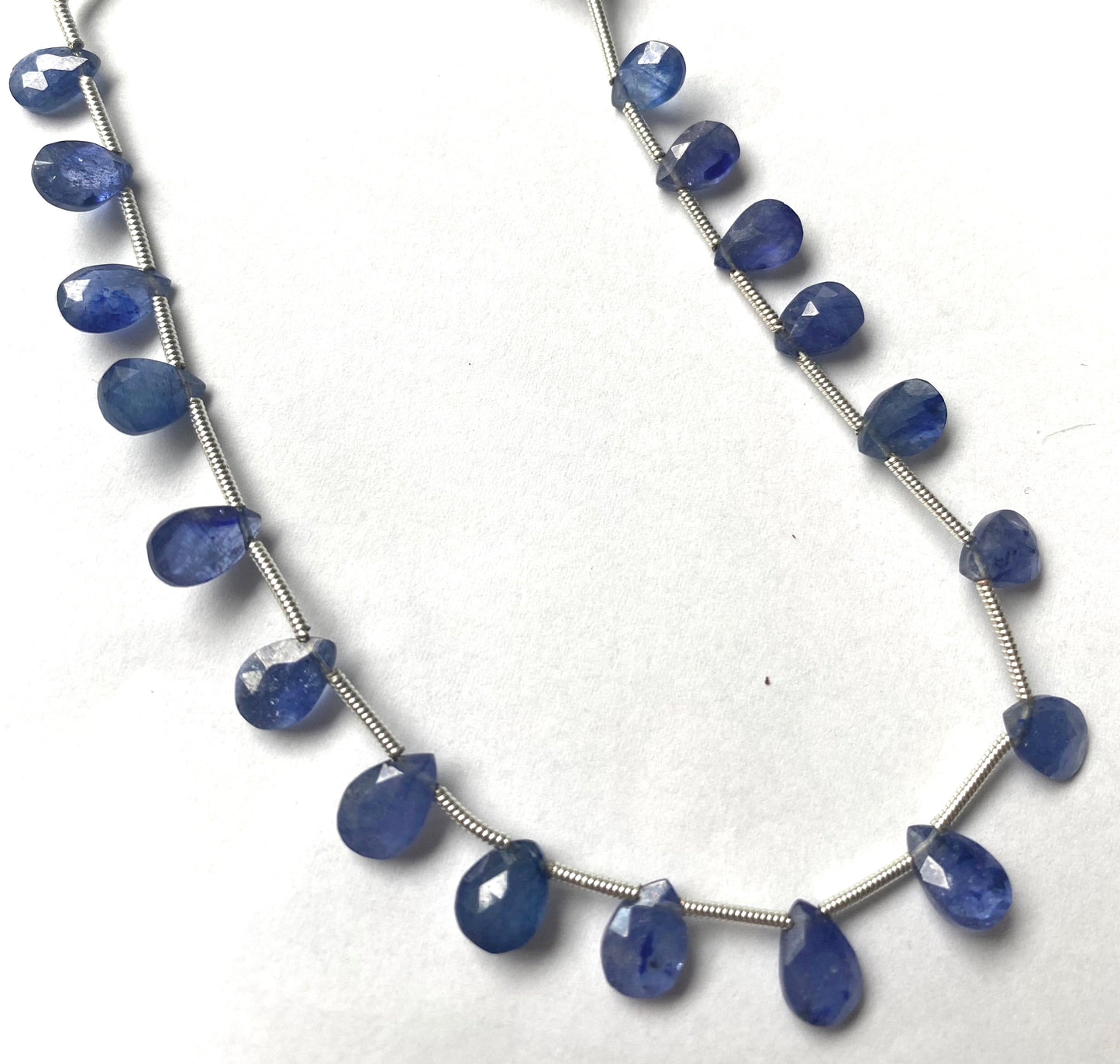 A strand of faceted blue sapphire almond shaped gemstone beads, measuring 7mm to 9mm, showcasing their vibrant colour and shine.