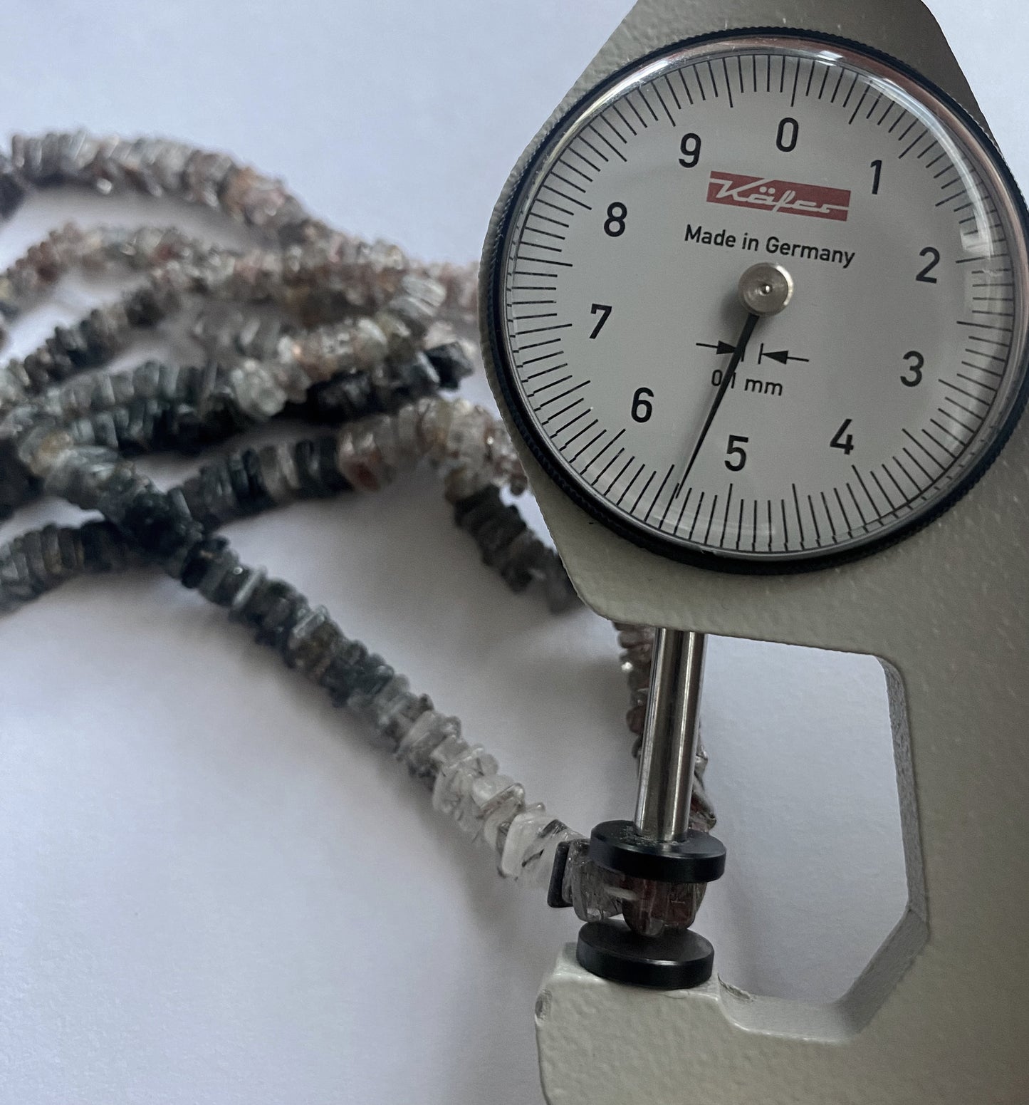A dial gauge measures the Change Garnet smooth square heishi 4–4.5mm gemstone.