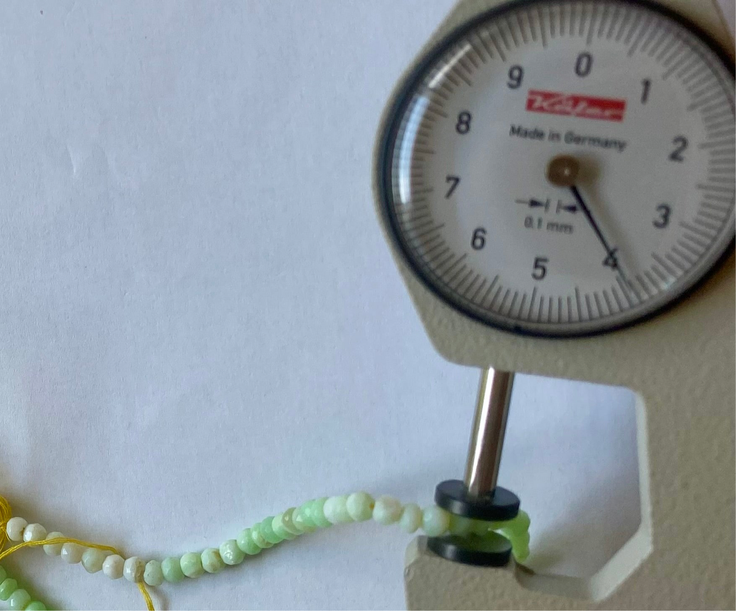 A dial gauge shows a green bead alongside a Chrysoprase gemstone strand crafted from 4-4.5mm faceted rondelle green beads.