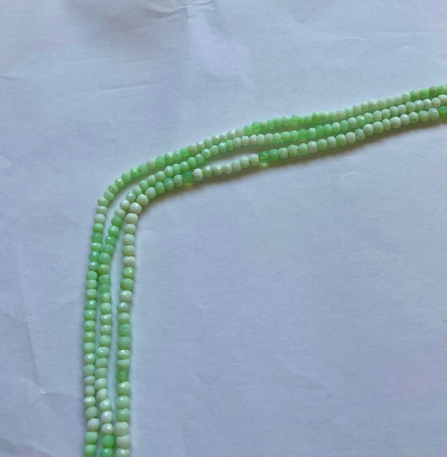 Green chrysoprase beads in faceted rondelle shape, 4.0-4.5mm, threaded in a strand for a vibrant, elegant look.