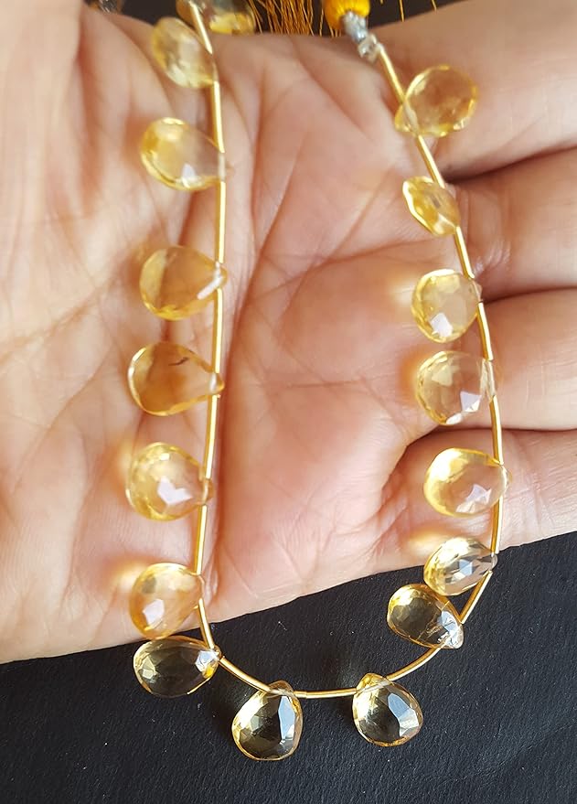 A strand of yellow citrine beads, featuring faceted pear shapes, showcasing their vibrant colour and shine.