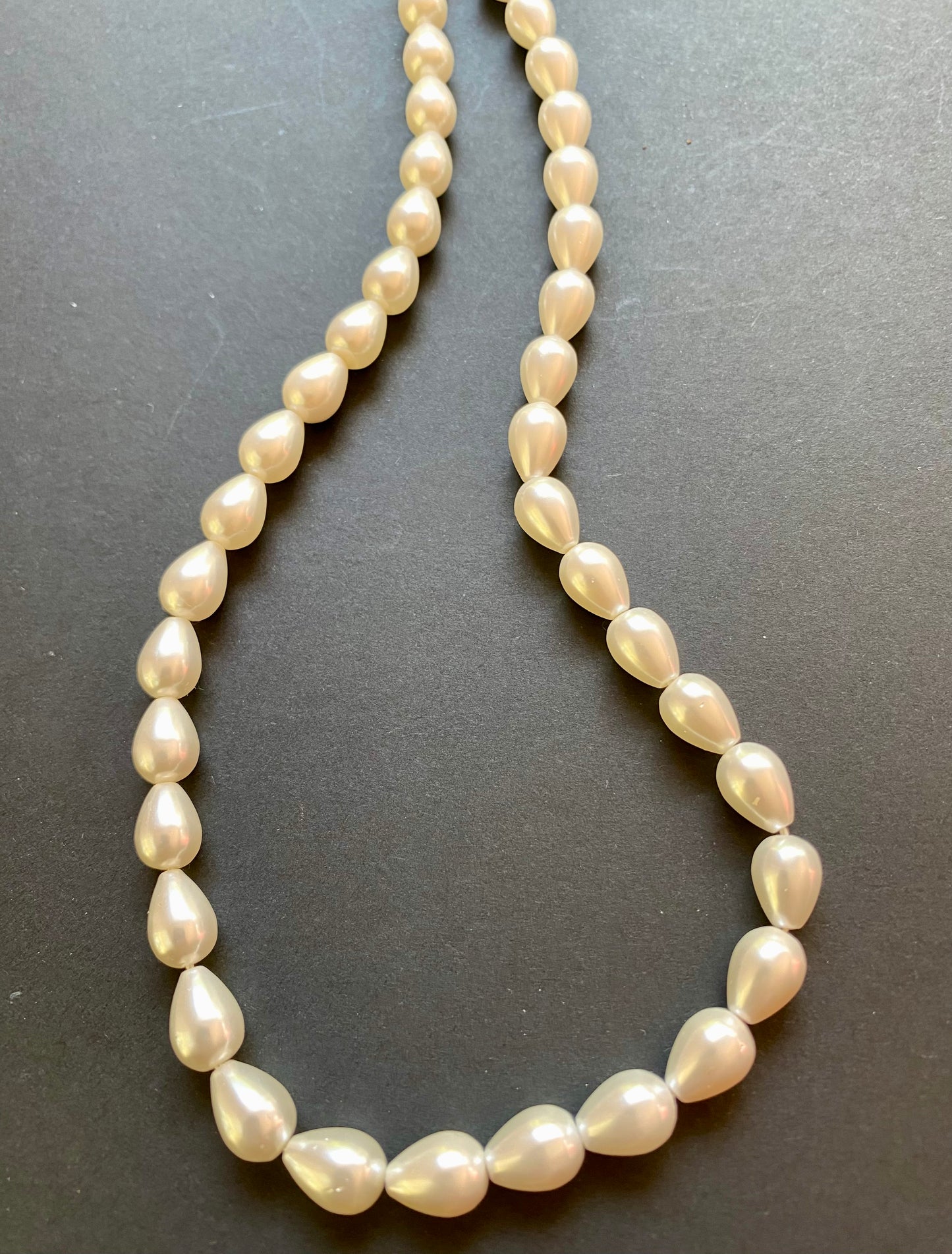 Close-up of a strand showcasing a lustrous cone pearl bead, highlighting its smooth surface and shine.