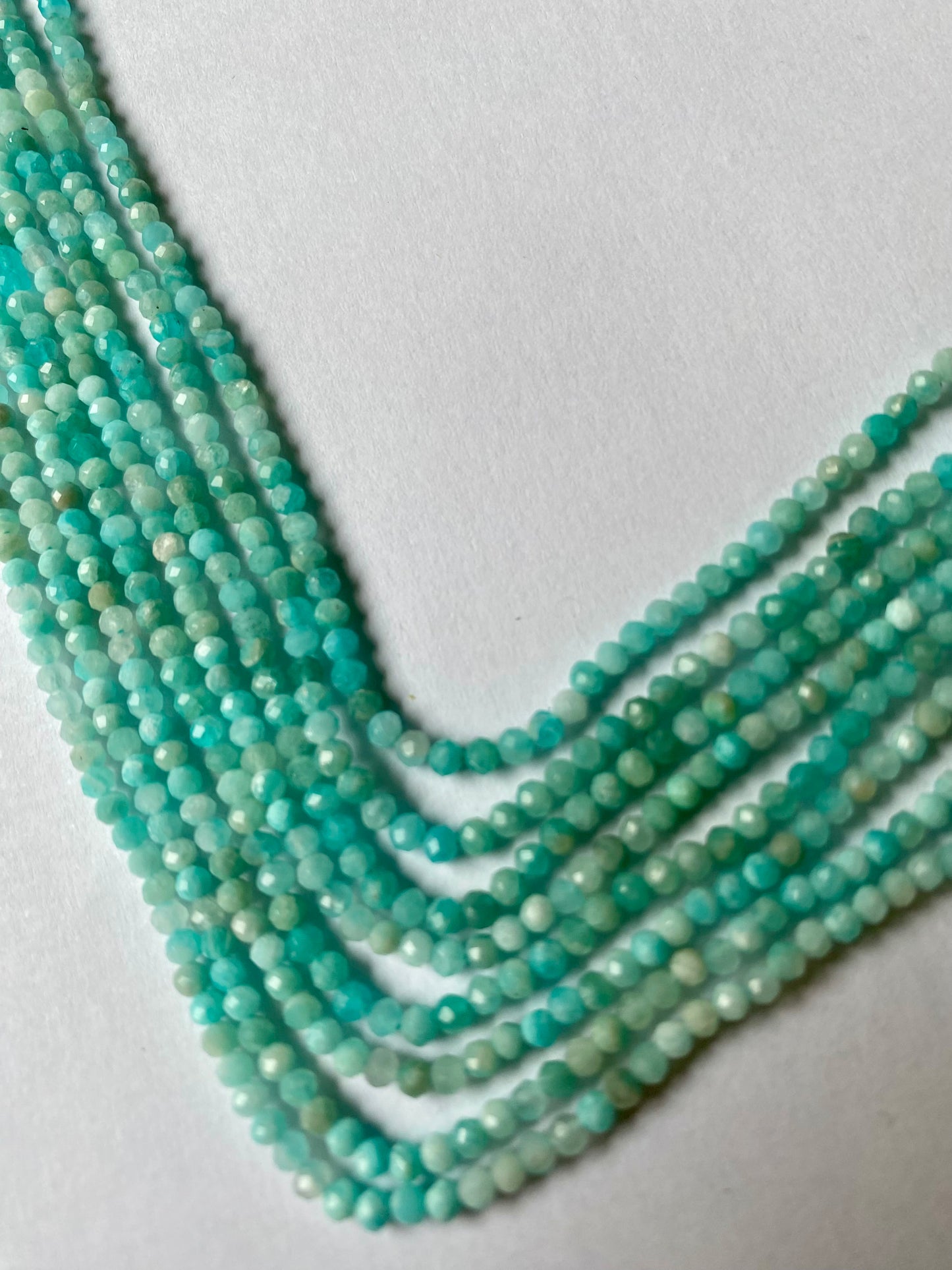 Strand of faceted Aquamarine beads arranged neatly for artisan beading projects.