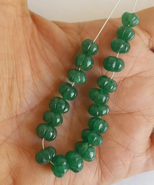 A close-up of a strand of green Emerald beads highlighting their carved rondelle design and rich hue.