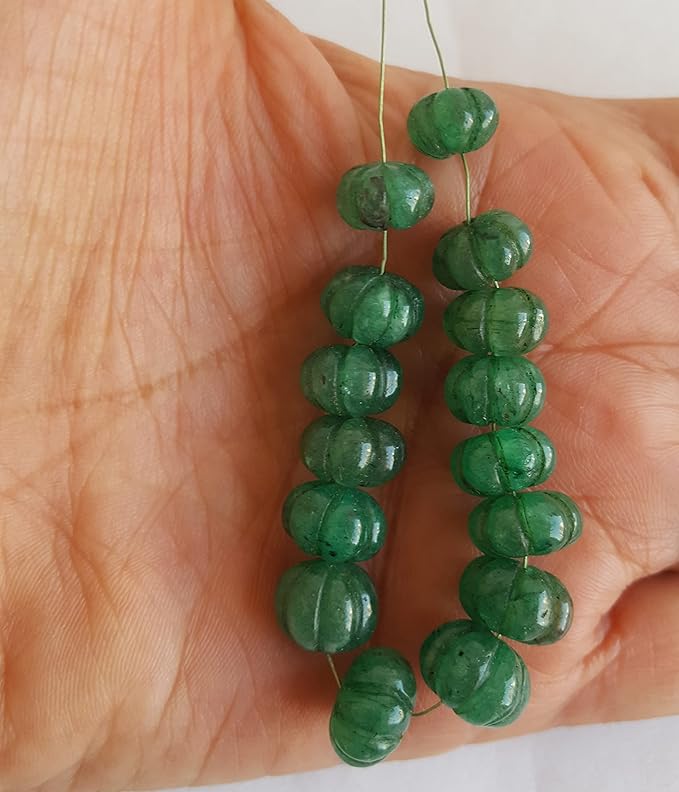 Close-up of a person holding a stunning green carved rondelle gemstone strand, highlighting its intricate facets.