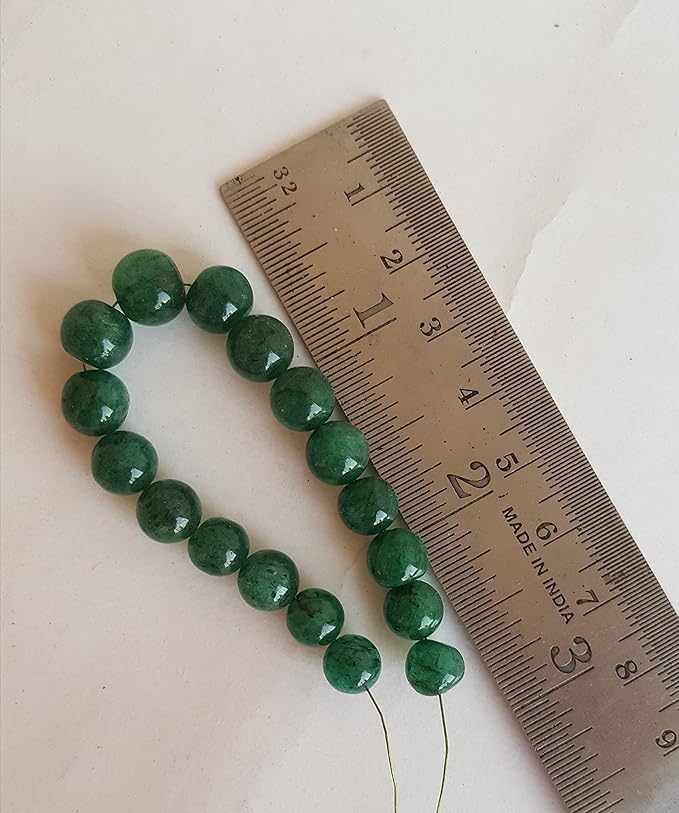 A measuring ruler and green Emerald beads are displayed closely, highlighting the beads' smooth round design & size.