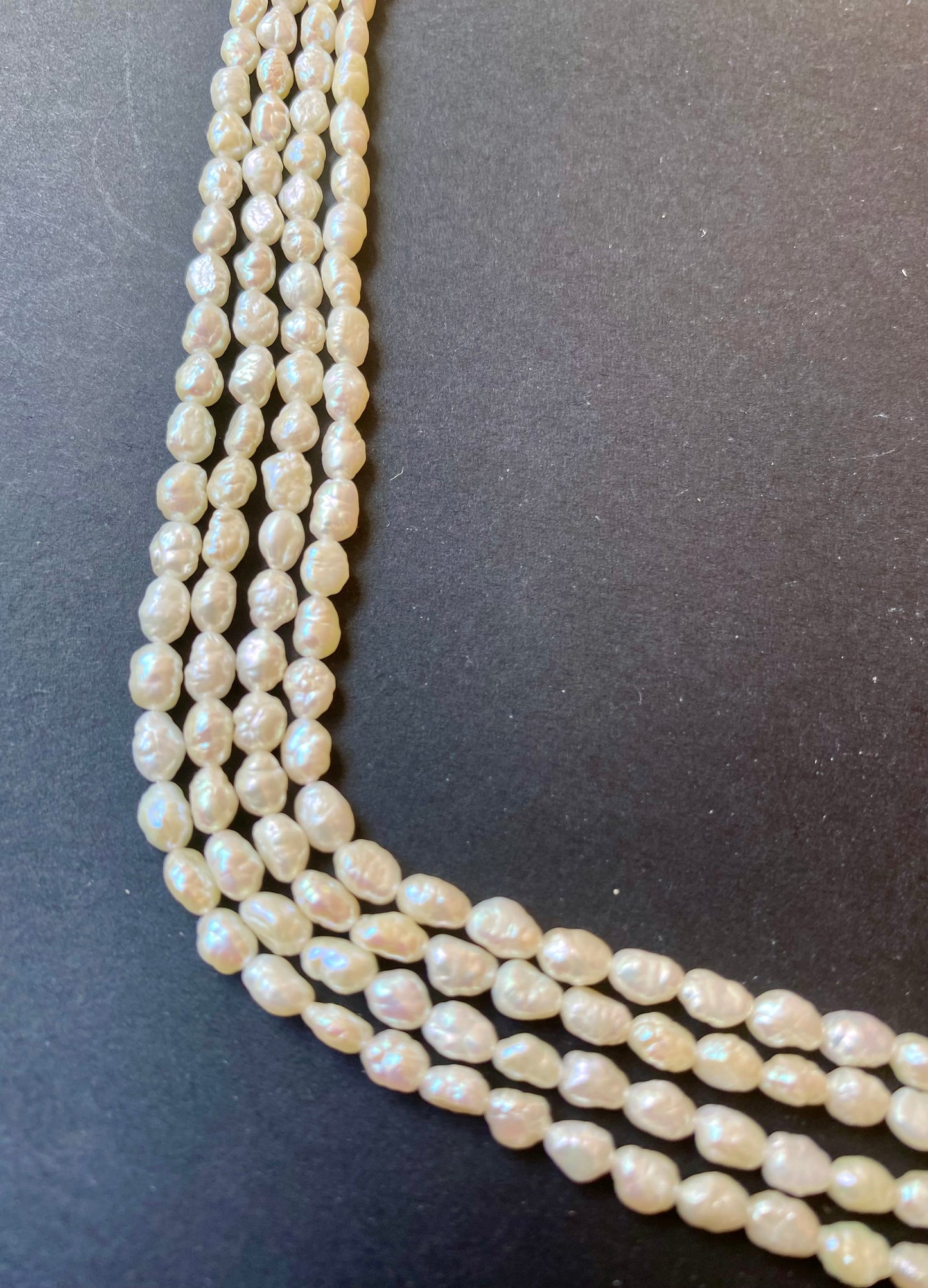Strands of freshwater Baroque rice pearls, showcasing beads of 3.2-3.7 mm on black surface.