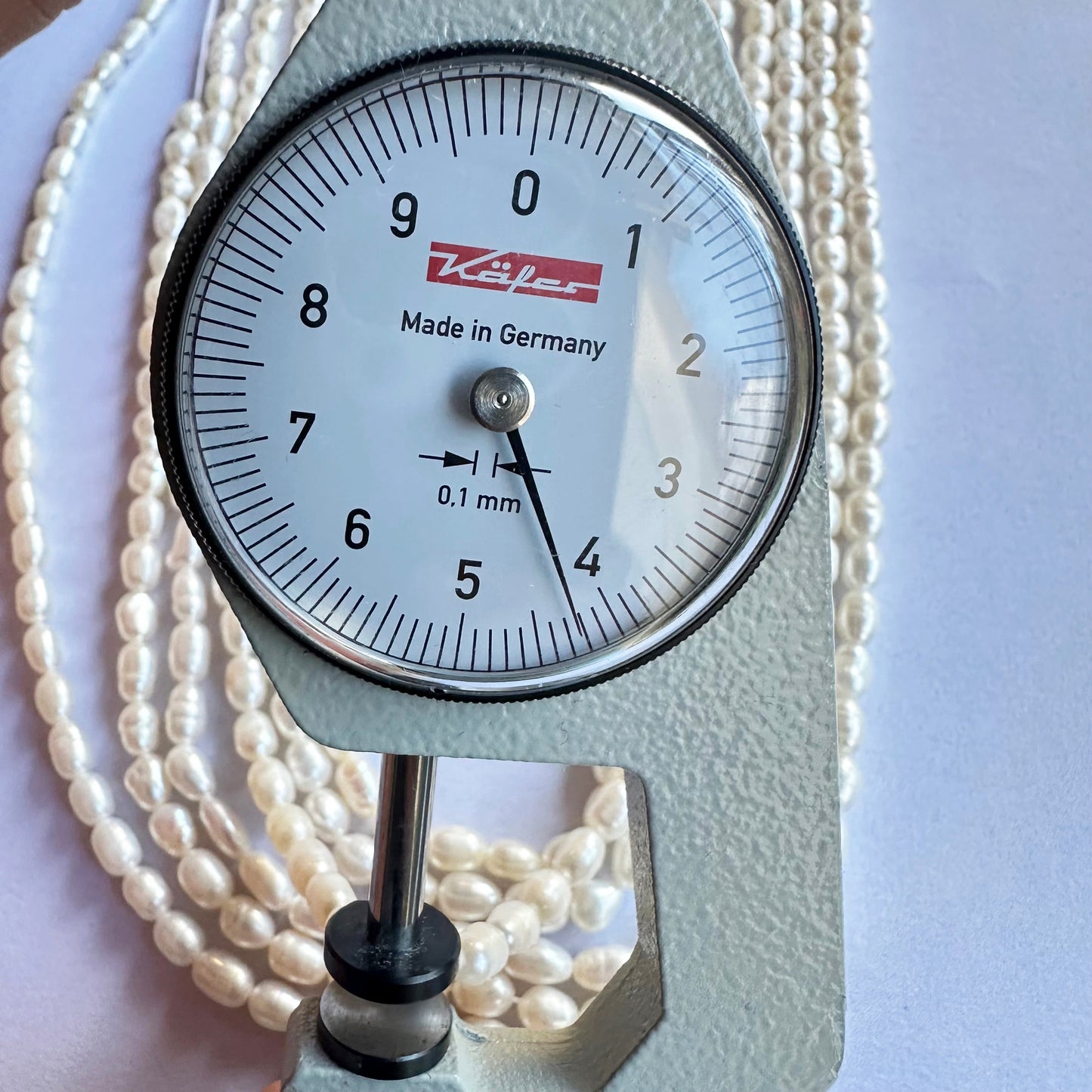 A dial gauge measures the Fresh Water Pearl smooth fancy shape 4mm to 4.5mm gemstone, ensuring size accuracy.