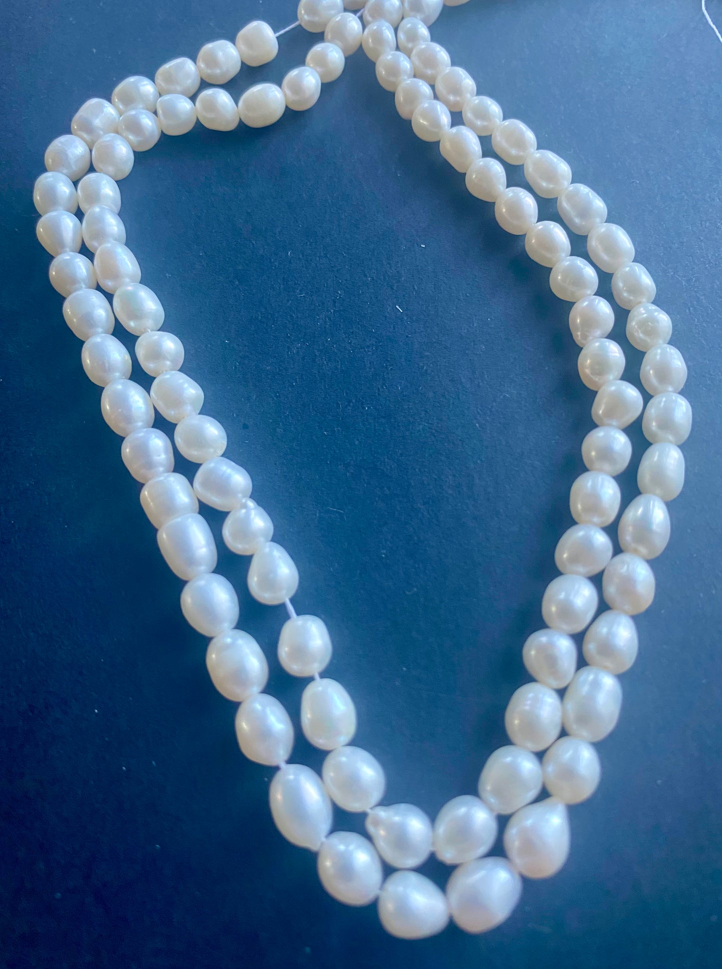 Beautiful strand of 6mm freshwater pearl beads resting on a sleek black background, showcasing their lustre.