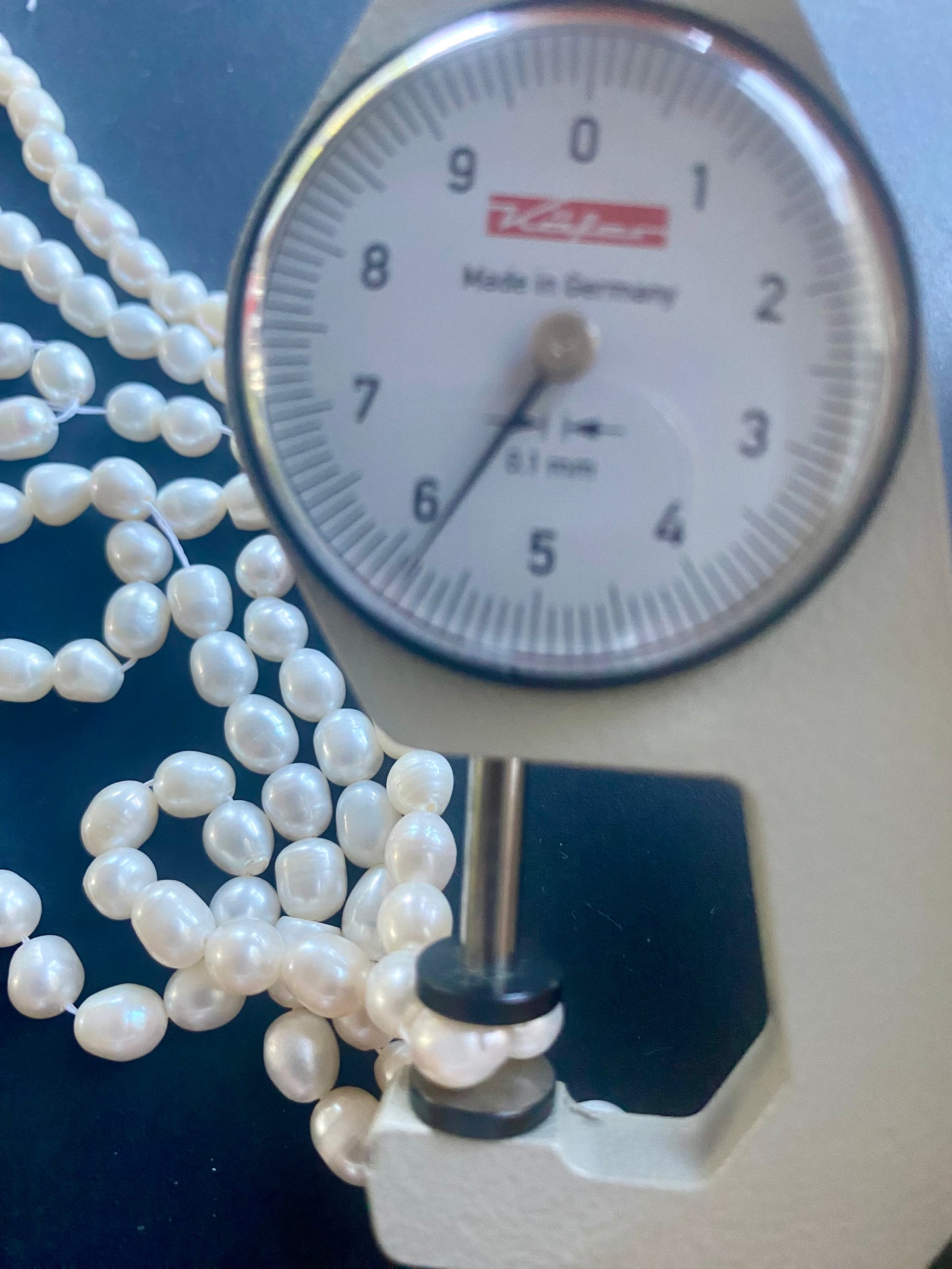 A dial gauge displaying a delicate 6mm freshwater pearl strand, highlighting size and measurement.