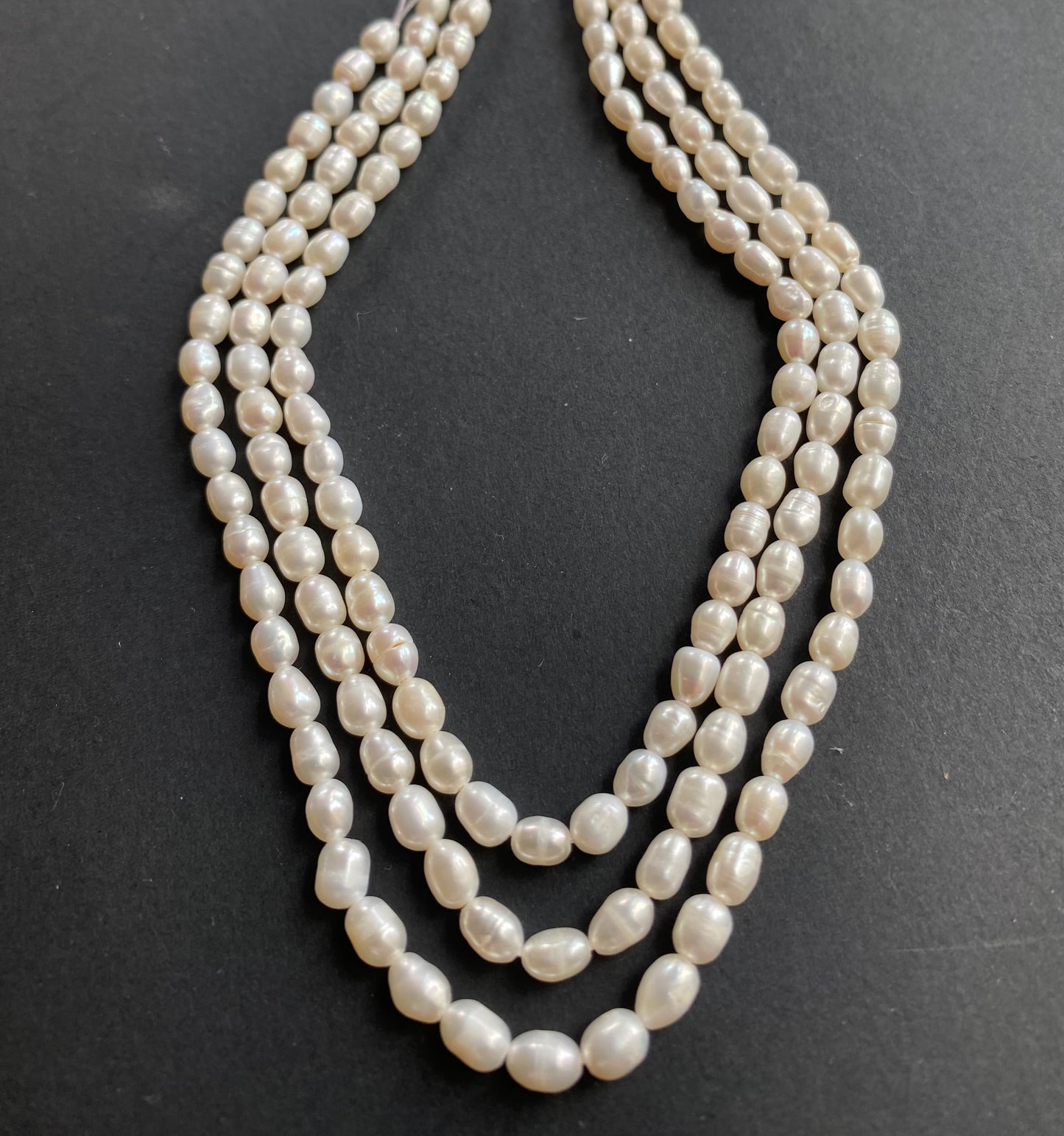 Beautiful strands of freshwater pearl bead gemstones resting on a sleek black background, showcasing their lustre.