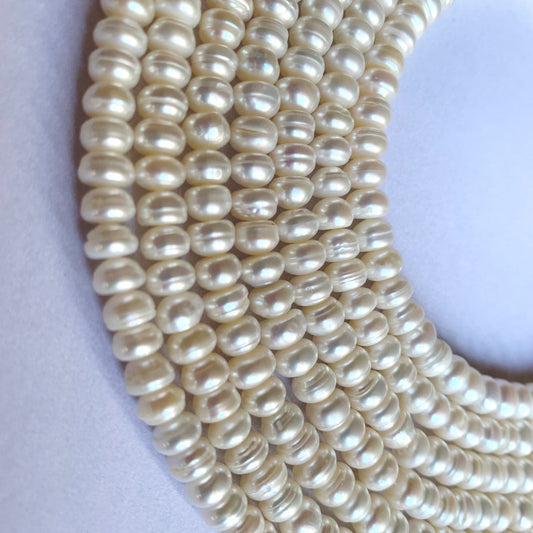Freshwater Pearl smooth rondelle beads are displayed in a cascading arrangement, showcasing their pristine beauty.