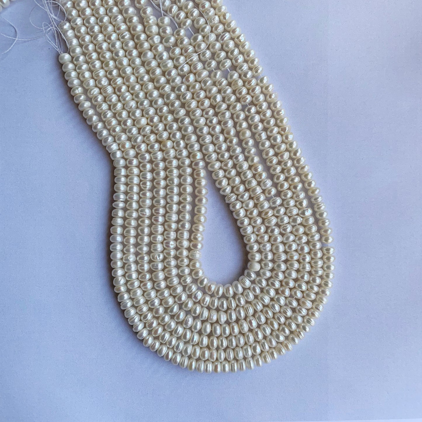 Strands of Freshwater Pearl beads shimmer under soft light, highlighting their smooth finish and high-quality craftsmanship.