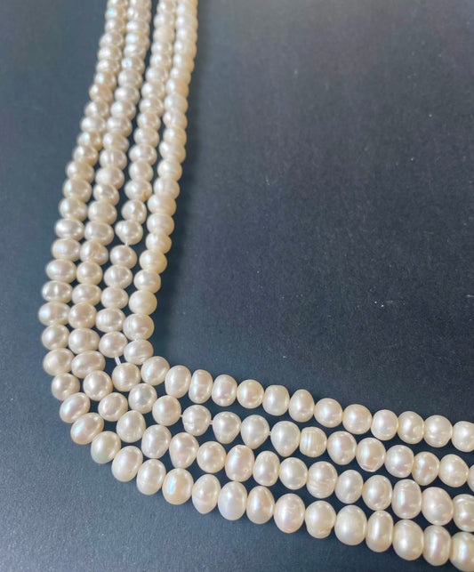Beautiful strands of 6-6.5mm freshwater rice pearls resting on a sleek black background, showcasing their lustre.