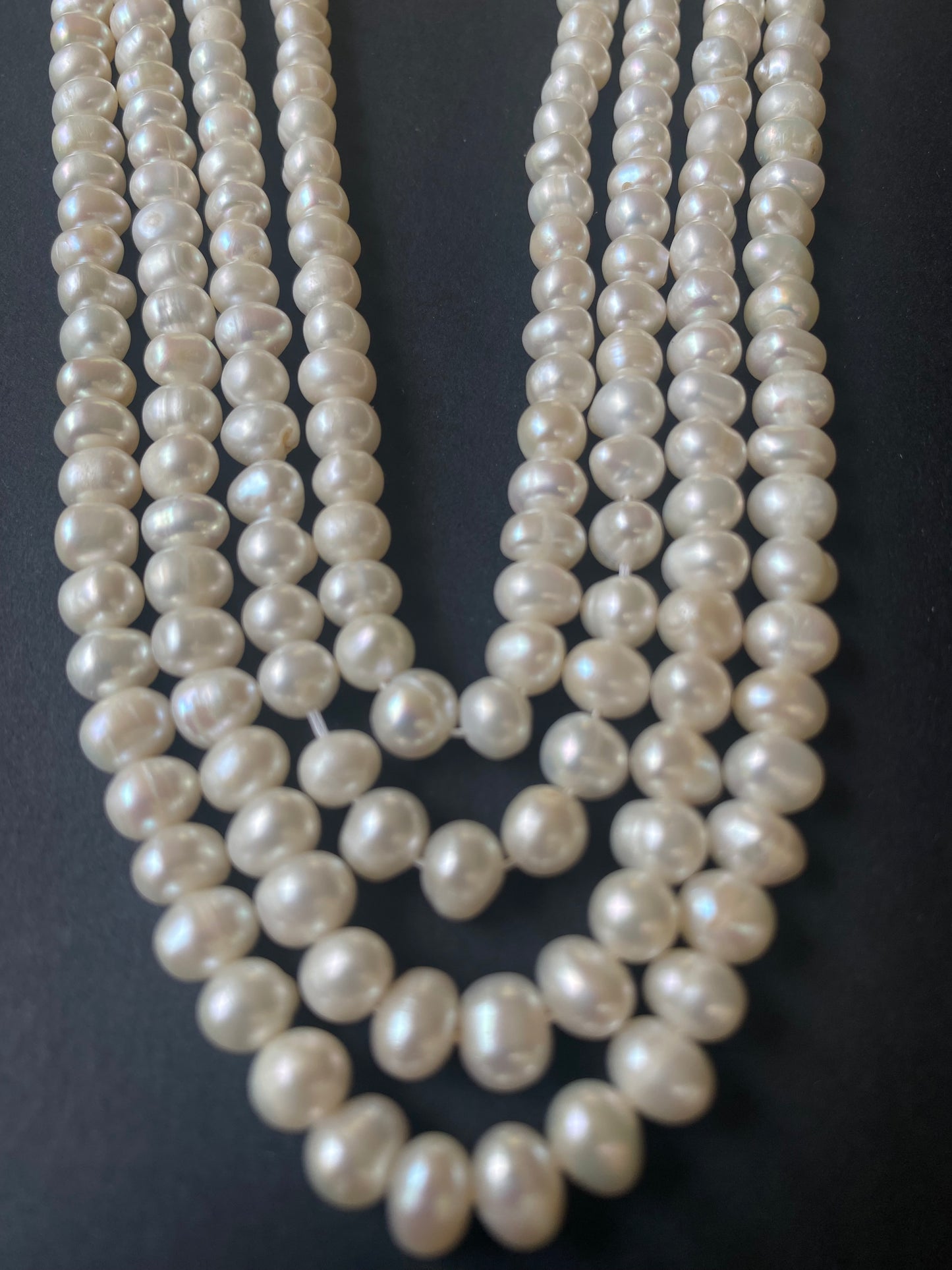 Delicate strands of 6-6.5mm freshwater rice pearls elegantly displayed on a smooth black surface.