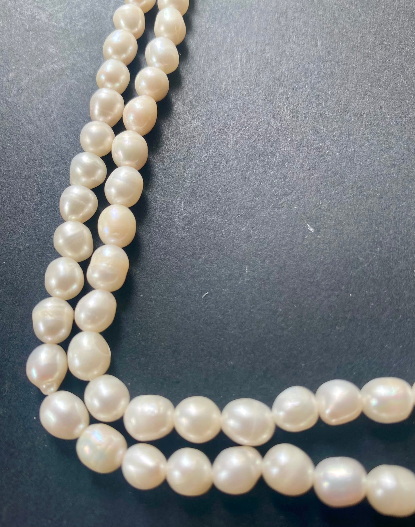 A beautiful strand of freshwater pearl beads resting on a sleek black background.