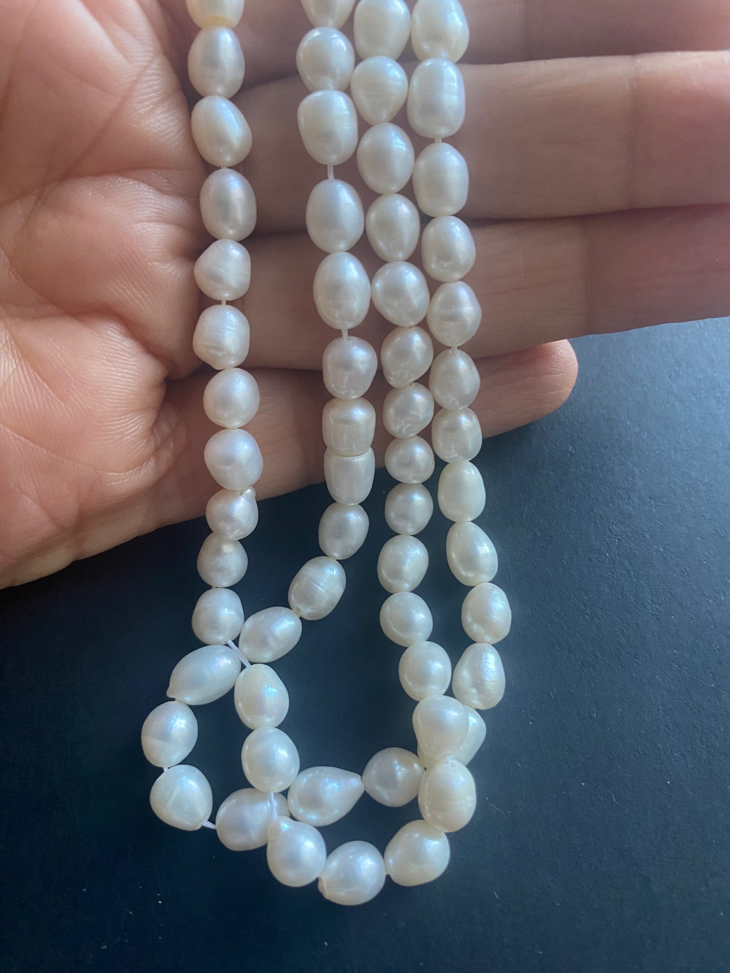 A hand delicately holds a strand of 6mm freshwater pearls, showcasing their lustre and elegance.