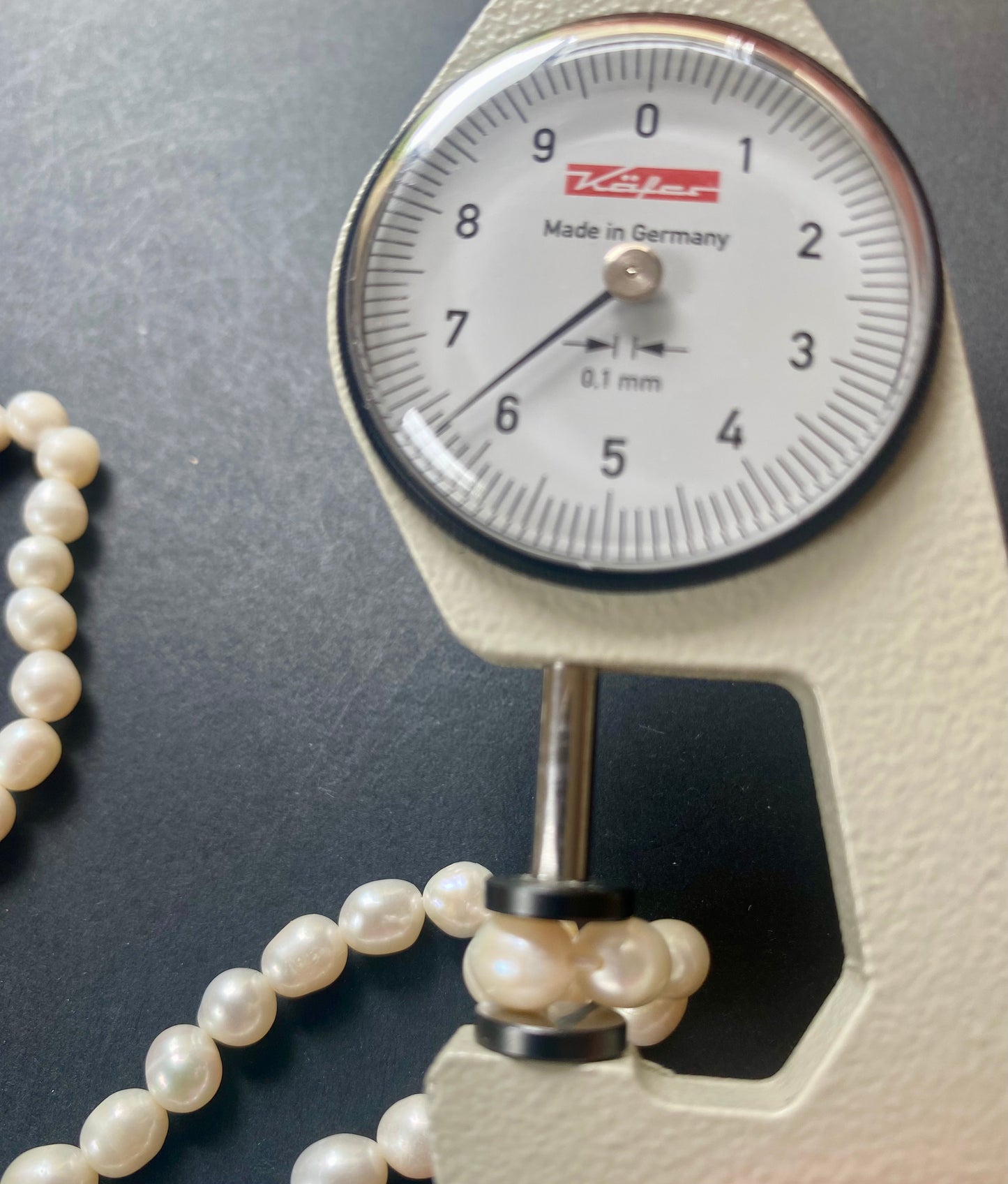 A dial gauge displaying a delicate 6-6.3mm freshwater pearl strand, highlighting size and measurement.