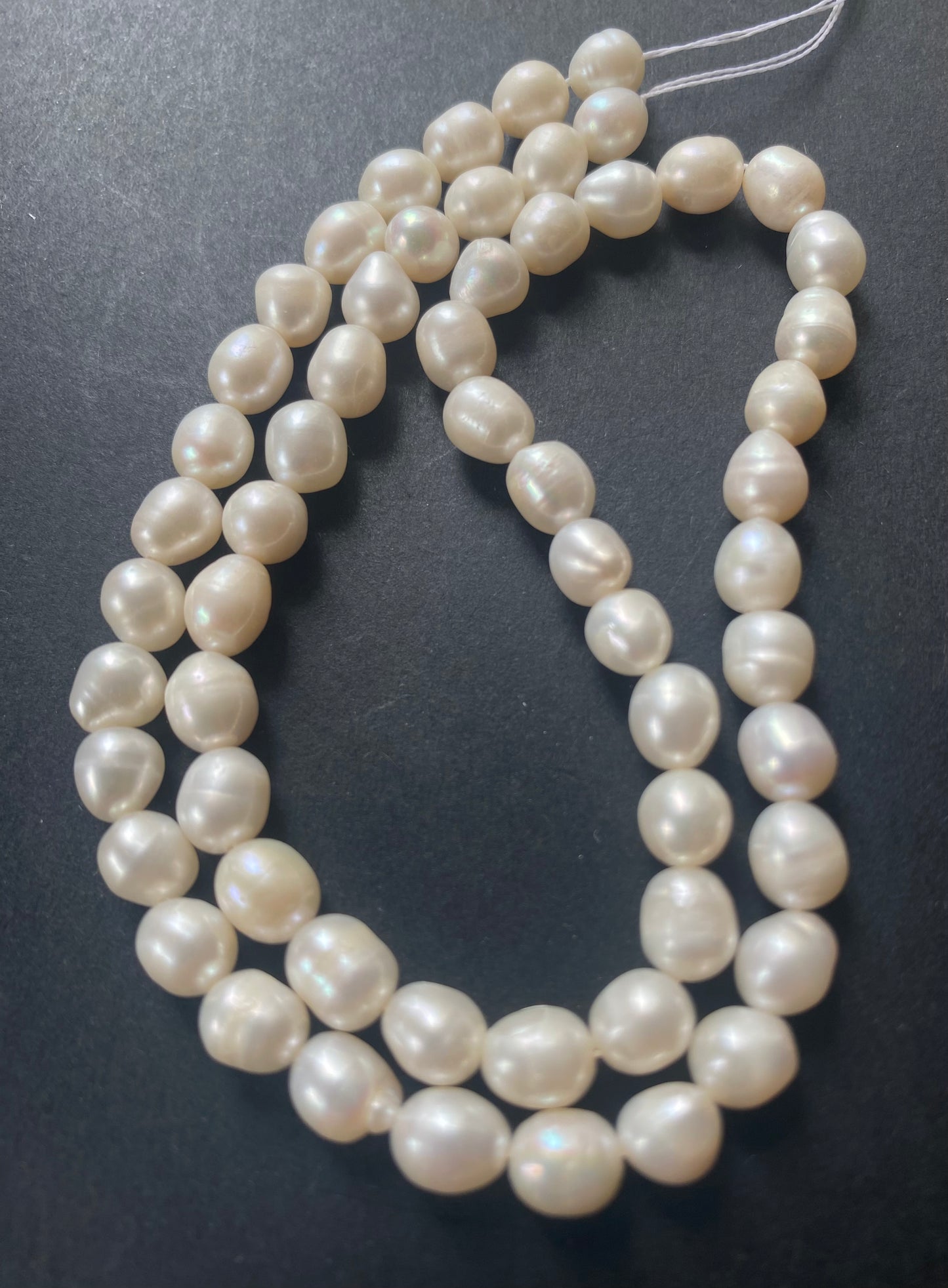A beautiful strand of 6-6.3mm freshwater pearl beads resting on a sleek black background, showcasing their lustre.