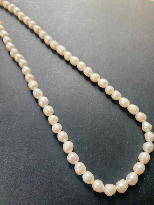 A delicate strand of 6-6.3mm freshwater pearl beads elegantly displayed on a smooth black surface.