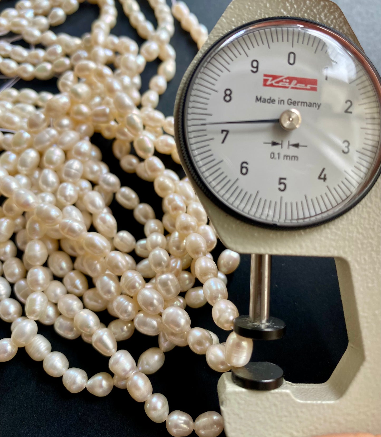 A dial gauge displaying a delicate freshwater rice pearl strand, highlighting size and measurement.