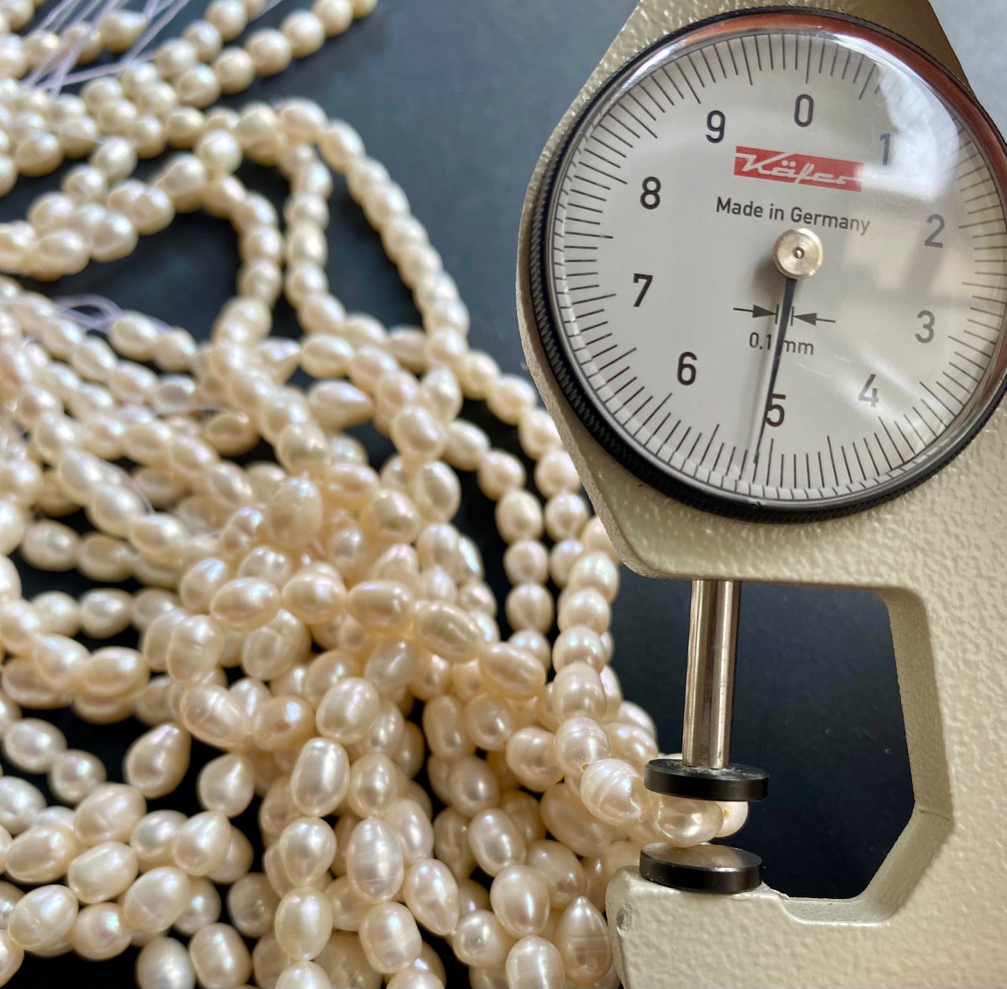 A dial gauge featuring a freshwater rice pearl strand, showcasing its size and measurement.